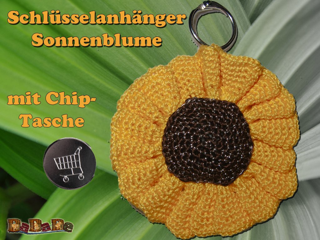 Gehäkelter Sonnenblumen-Schlüsselanhänger mit Chipfach und Metallring auf grünem Blatt