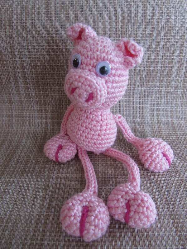 Rosa gehäkeltes Amigurumi-Schwein mit Wackelaugen und langen Beinen