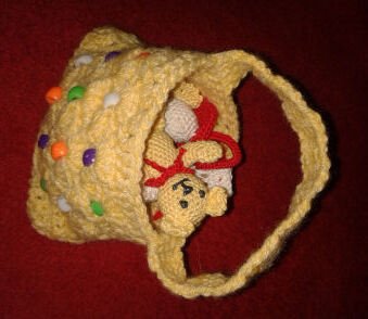 Gelbe Häkeltasche mit bunten Perlen und kleinem Teddybär auf rotem Hintergrund