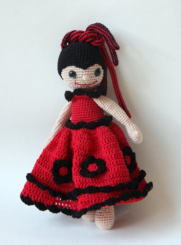 Gehäkelte Amigurumi-Puppe in rot-schwarzem Rüschenkleid mit schwarzen Blumenapplikationen und roten Haarsträhnen
