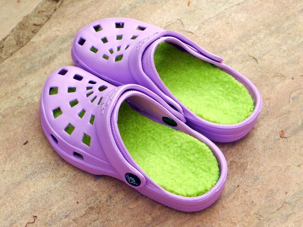 Lavender slip-on clogs with lime-green felted liners on a stone surface