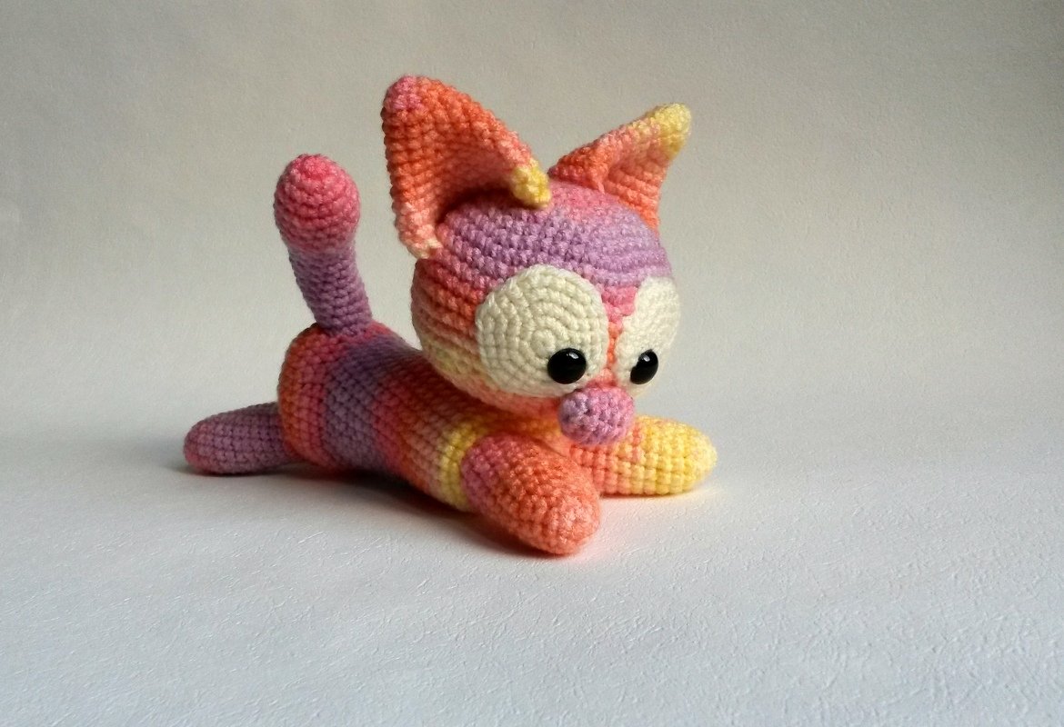 Gehäkeltes Amigurumi-Kätzchen in Pastell, liegend mit großen Augen