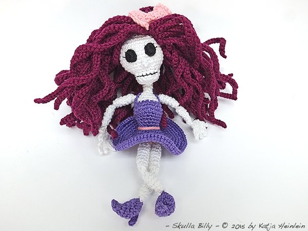 Gehäkelte Amigurumi-Skelettpuppe mit burgunderroten Haaren und lila Kleid
