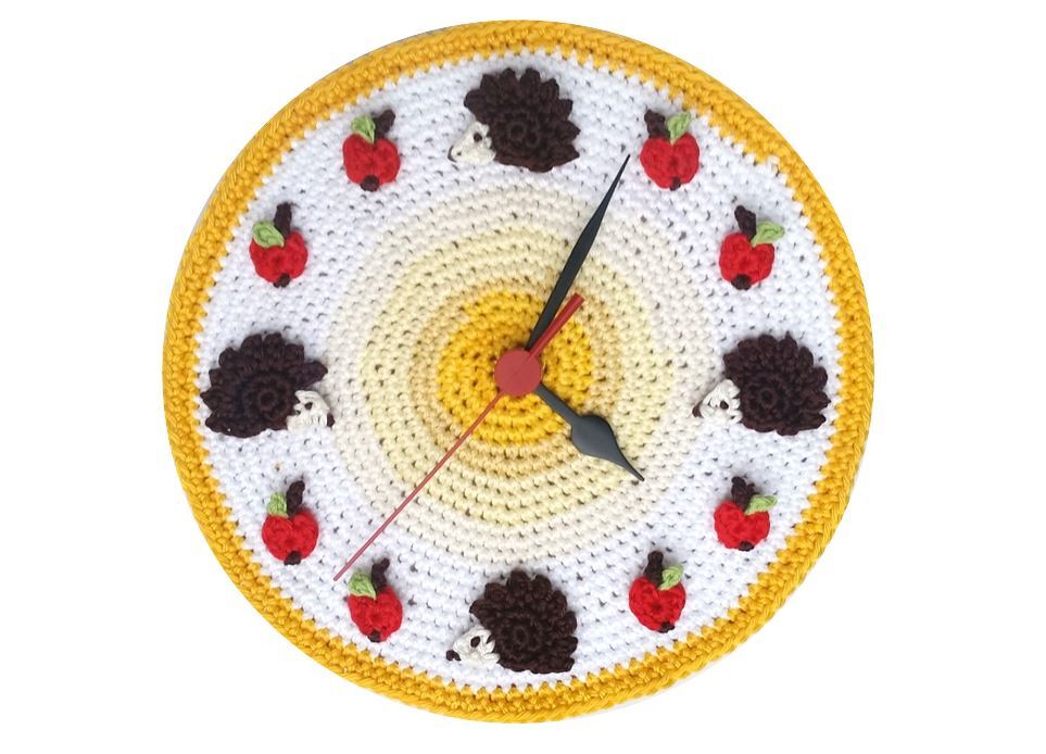 Gehäkelte runde Wanduhr mit Igel- und Apfelapplikationen in Weiß, Gelb und Rot