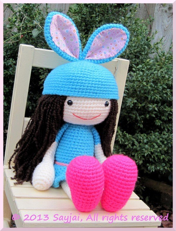Amigurumi-Puppe mit blauer Mütze, Hasenohren und rosa gehäkelten Schuhen