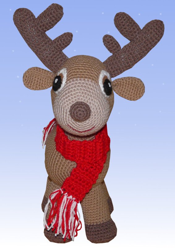 Gehäkeltes Rentier-Amigurumi in Braun mit Geweih und rot-weißem Schal vor hellblauem Hintergrund