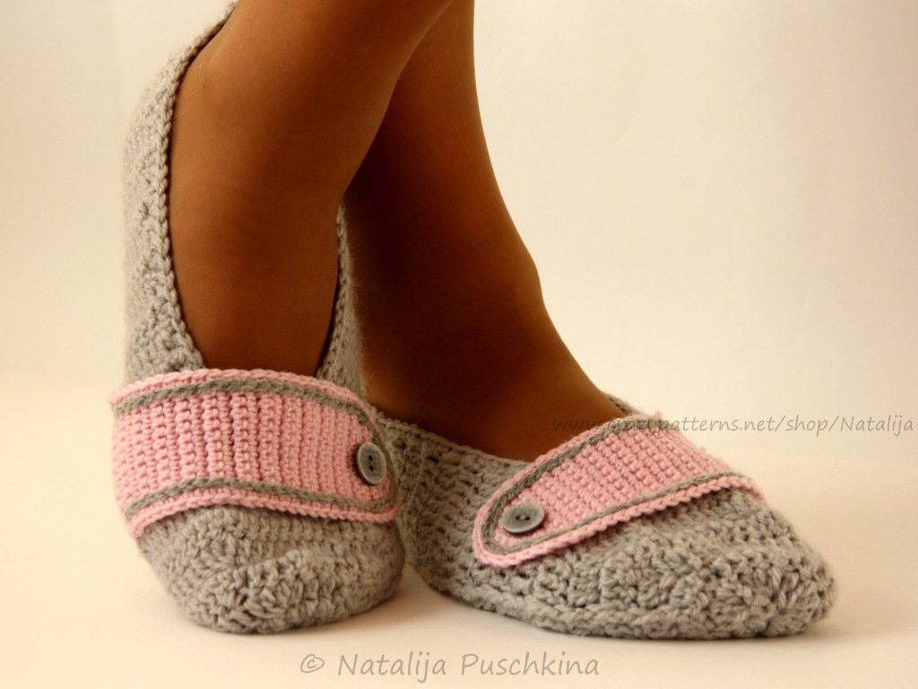 Gehäkelte hellgraue Ballerinas mit rosa Riemen und Knopf an den Füßen