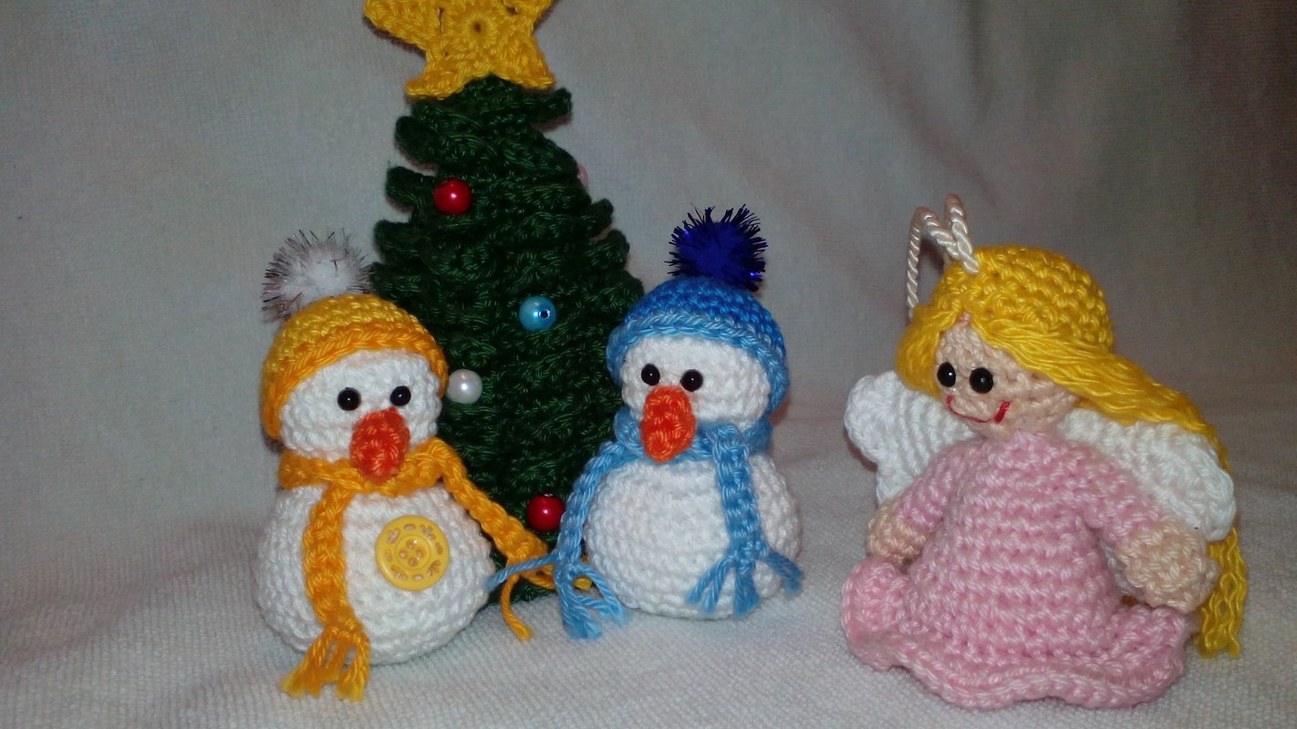 Zwei gehäkelte Schneemänner, ein geschmückter Weihnachtsbaum und ein gehäkelter Engel