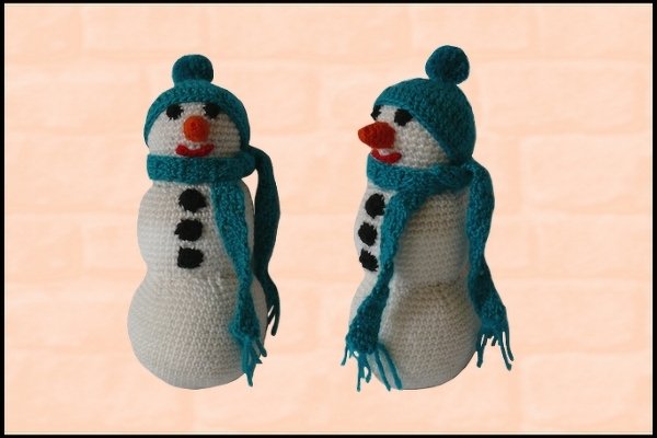 Zwei gehäkelte Schneemänner, weiß, mit türkiser Mütze und Schal, orangefarbener Nase und schwarzen Knöpfen