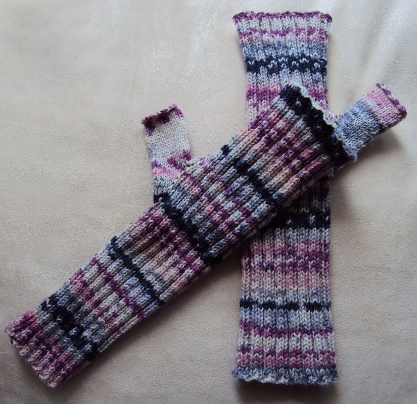 Gestrickte, fingerlose Armstulpen in Lila-, Pink-, Blau- und Cremefarben mit Rippenmuster und dunklen Querstreifen.