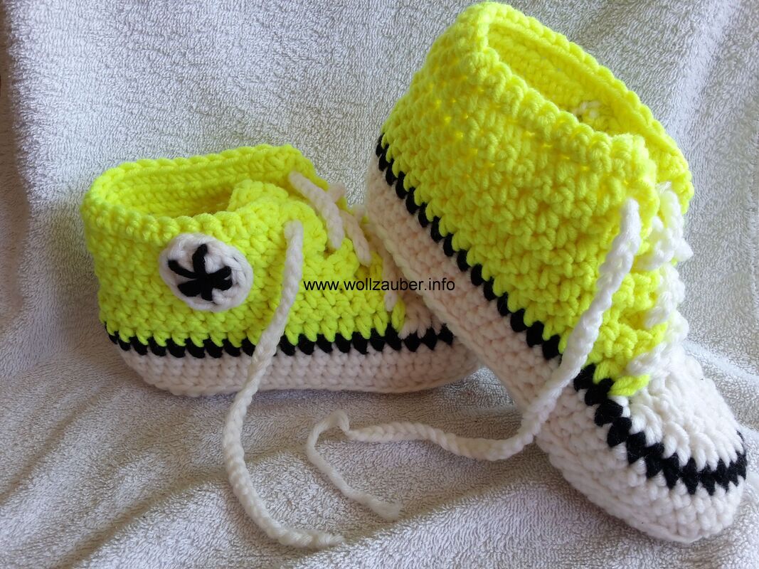 Neongelbe gehäkelte Babyschuhe im Sneaker-Look mit weißen Schnürsenkeln und schwarzen Akzenten
