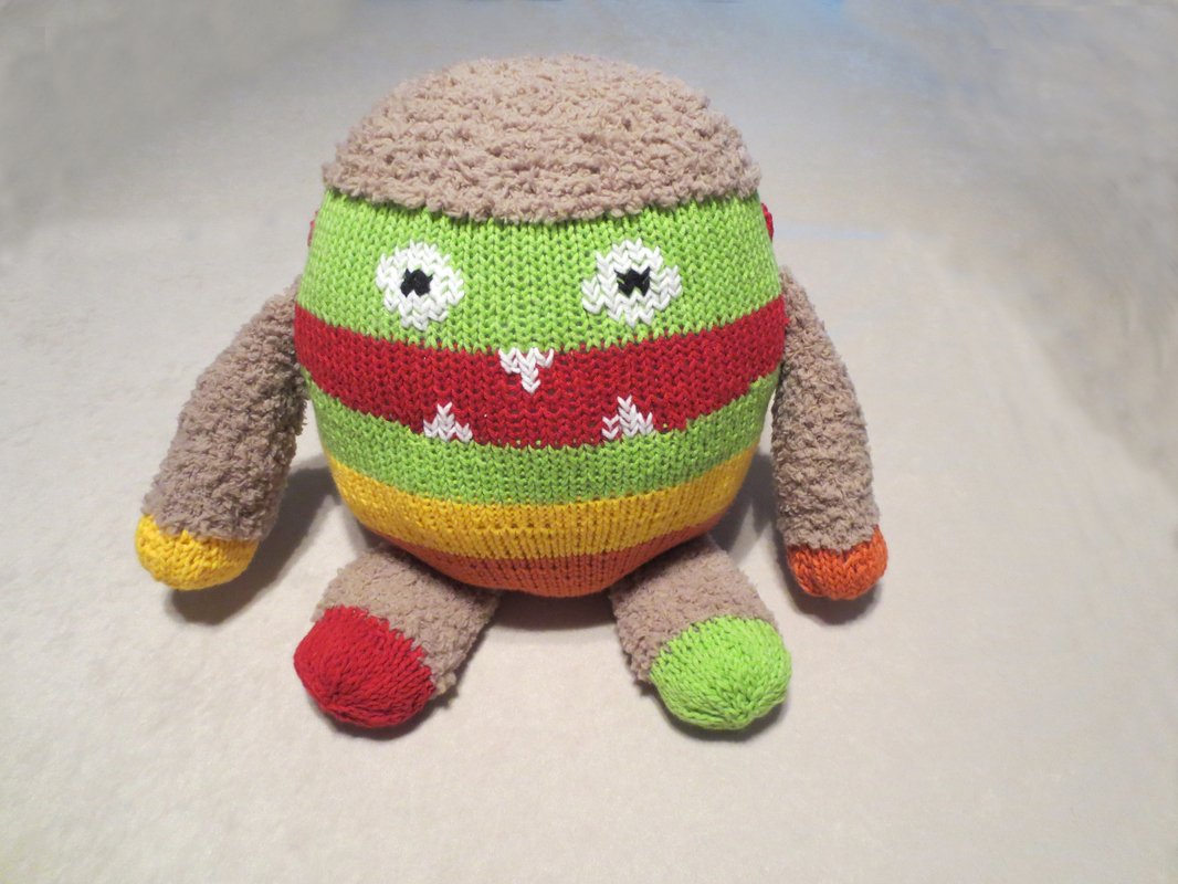 Gestricktes rundes Amigurumi-Kuschelmonster mit bunten Streifen