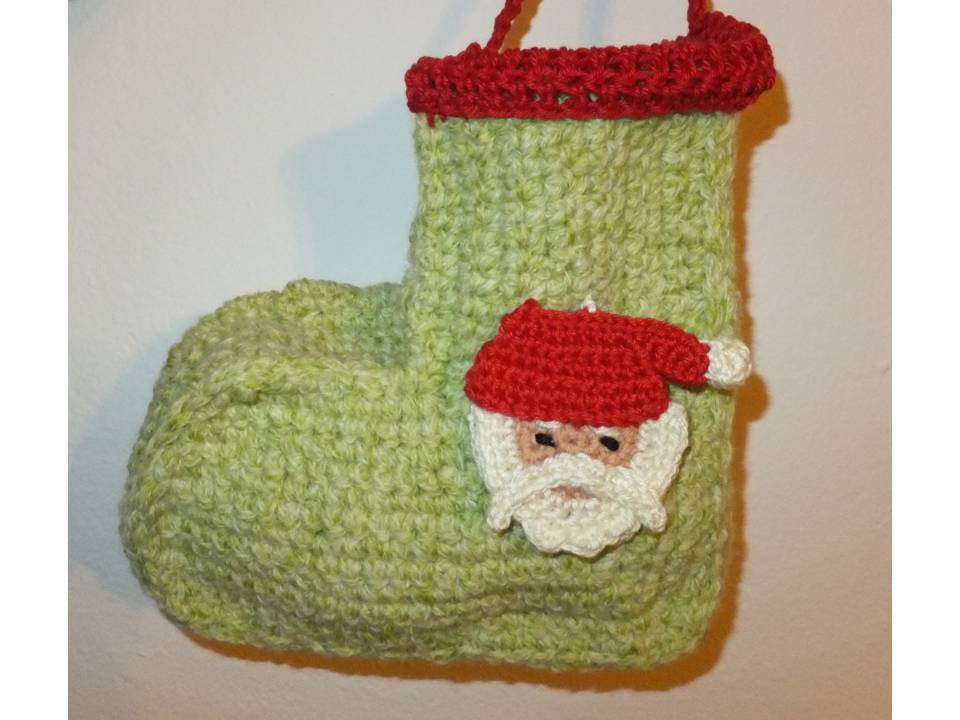 Gehäkelter hellgrüner Nikolausstiefel mit rotem Rand und gehäkeltem Weihnachtsmannkopf, hängend.
