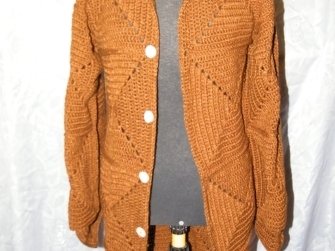 Rostbraune gehäkelte Damenjacke mit diagonalem Muster und hellen Knöpfen an einer Schaufensterpuppe