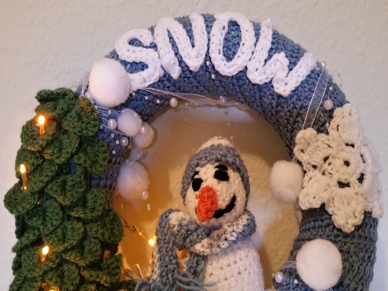 Gehäkelter Türkranz in Blaugrau mit Schneemann, gehäkelter Tanne, Pompons und Schneeflocke