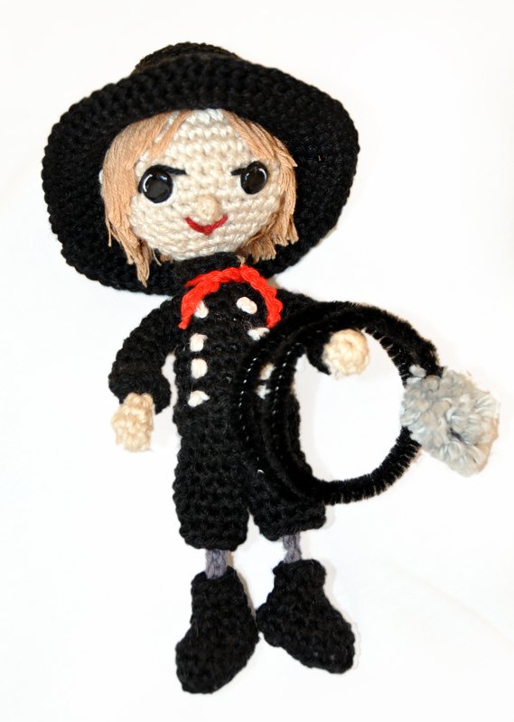 Gehäkelte Schornsteinfeger-Puppe in schwarzem Anzug und Hut, hält schwarzen Ring mit grauem Bommel