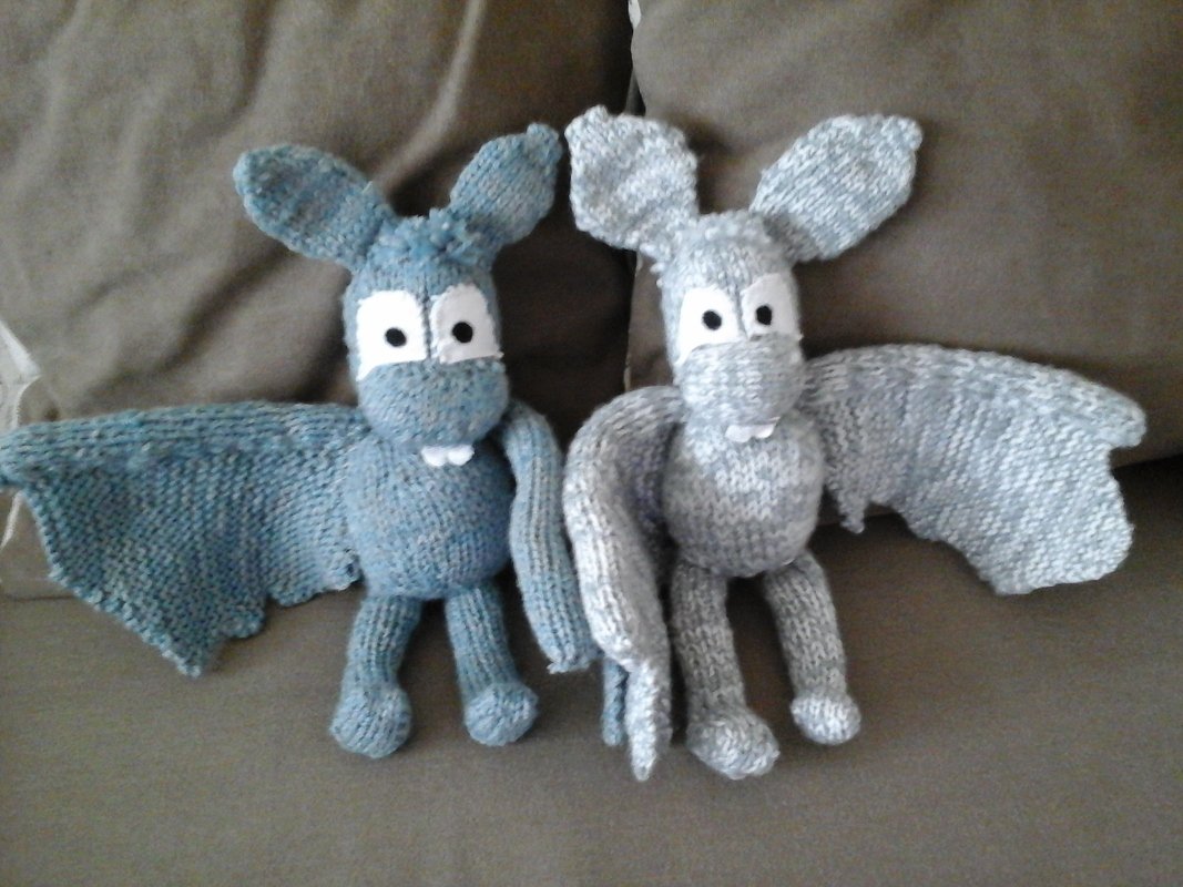 Zwei gestrickte Fledermaus-Amigurumis in Blau und Hellgrau mit großen weißen Augen und Flügeln