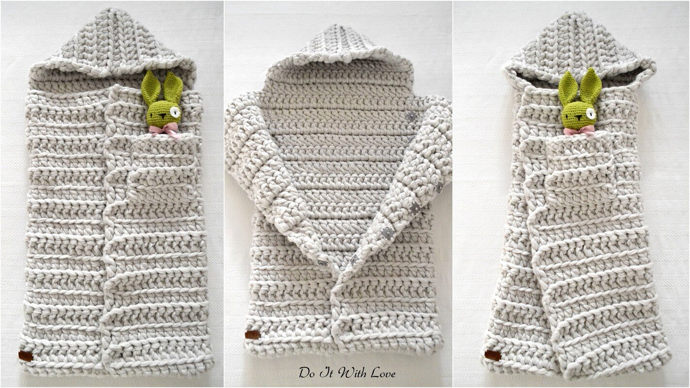 Light grey crocheted baby cocoon with hood and side button closure, a small green crocheted rabbit peeking from the opening.