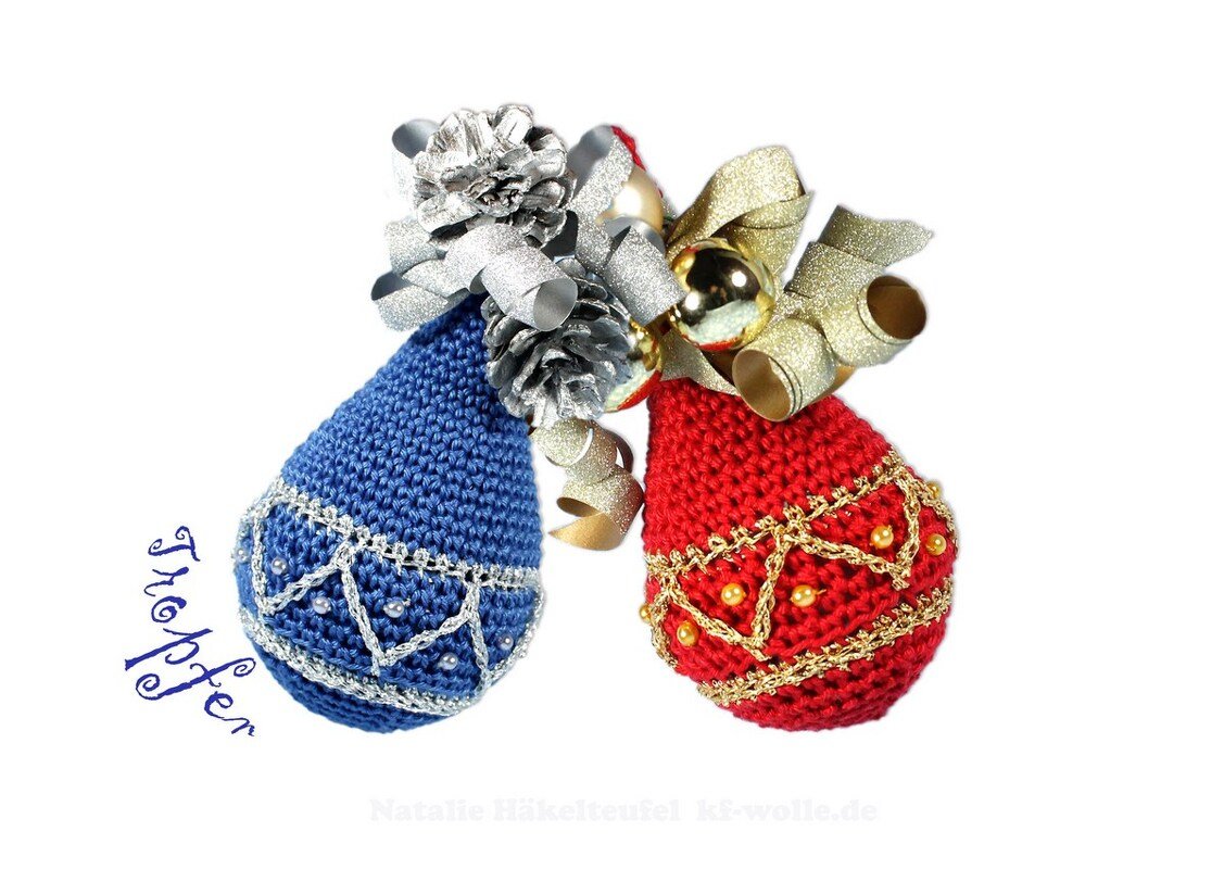 Nahaufnahme von zwei gehäkelten Weihnachtskugeln in Blau und Rot mit Perlen, dekorativen Borten, Schleife und Zapfen