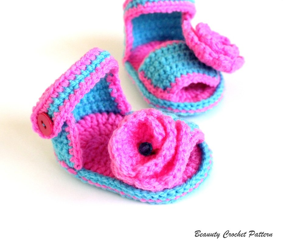 Pair of pink and turquoise crochet baby sandals with button strap and flower embellishment