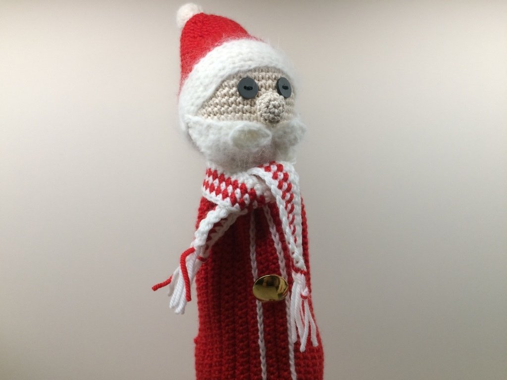 Gehäkelter Weihnachtsmann mit roter Mütze, weißem Bart, gestreiftem Schal und kleinem Glöckchen