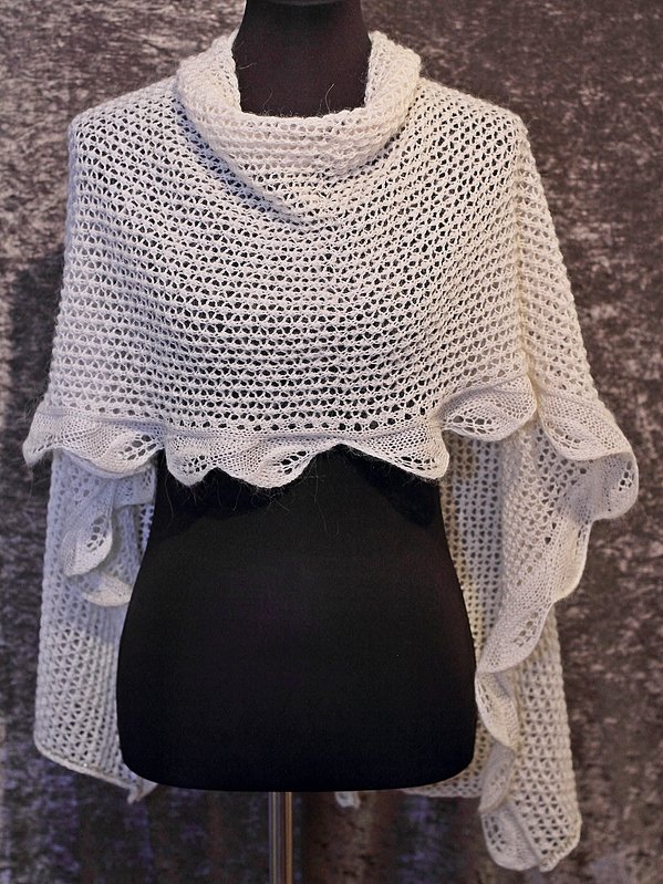 Mannequin wearing an ivory rectangular openwork shawl with a scalloped ruffle edge