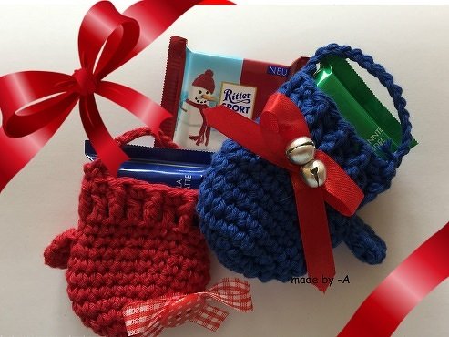 Zwei gehäkelte Mini-Säckchen in Rot und Blau mit Schleifen, Glöckchen und Süßigkeiten