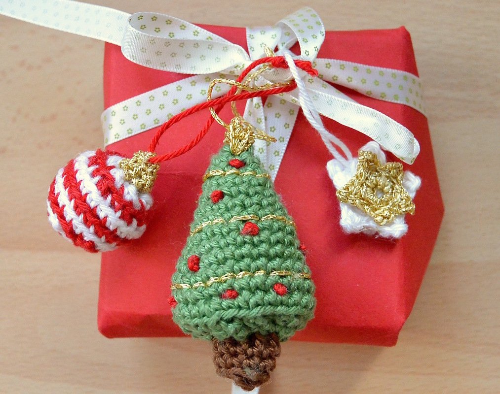 Gehäkelte Weihnachtsanhänger: grüner Tannenbaum, rot-weiße Kugel und weißer Stern auf roter Geschenkbox