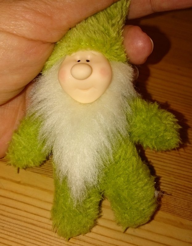 grüner Nähwichtel mit weißem Bart und Hand als Größenvergleich