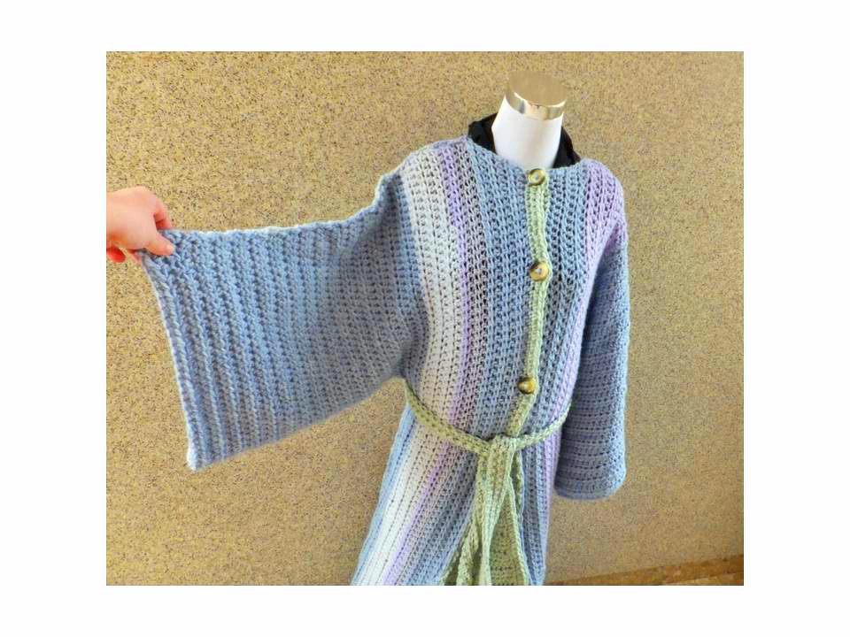 Gehäkelte Pastelljacke auf Mannequin mit weiten Ärmeln, Knopfleiste und geflochtenem Gürtel