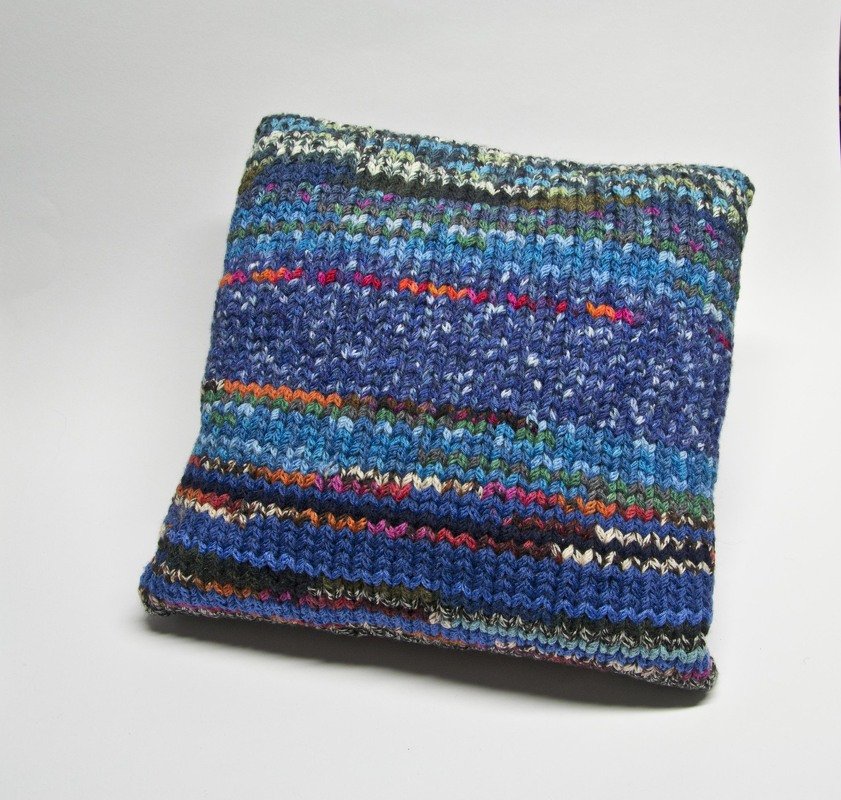 Gestrickter Kissenbezug in Blautönen mit bunten Streifen, frontal