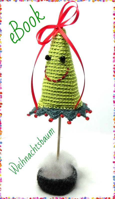 Gehäkelter grüner Mini-Weihnachtsbaum mit Gesicht, Perlenrand und roter Schleife auf Holzstäbchen in gehäkelter Basis
