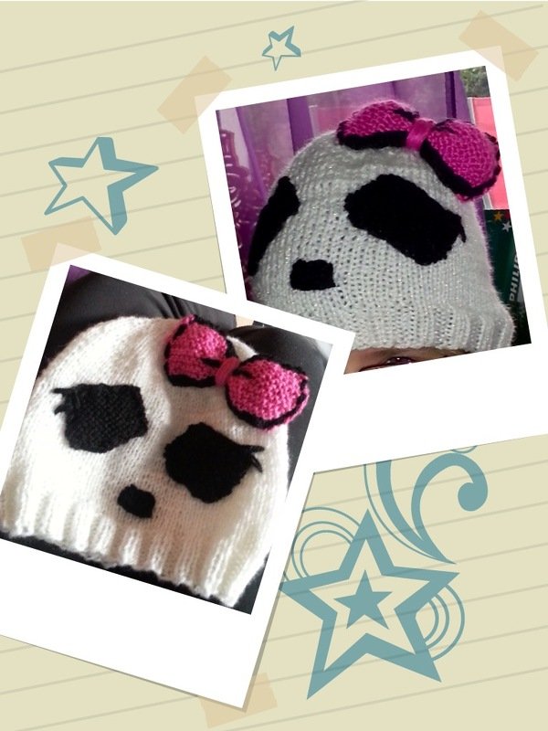 Gestrickte weiße Mütze mit schwarzen Motivflächen und pinker Schleife