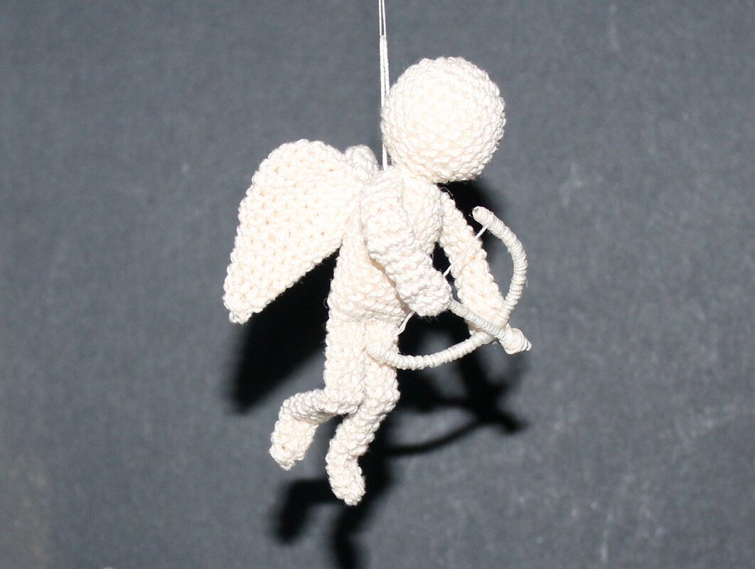 Helles Amigurumi-Engelchen mit Flügeln und kleinem Bogen, hängend