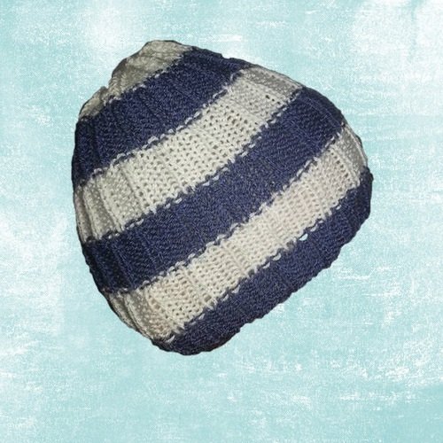 Gestrickte blau-weiß gestreifte Mütze vor hellem Hintergrund
