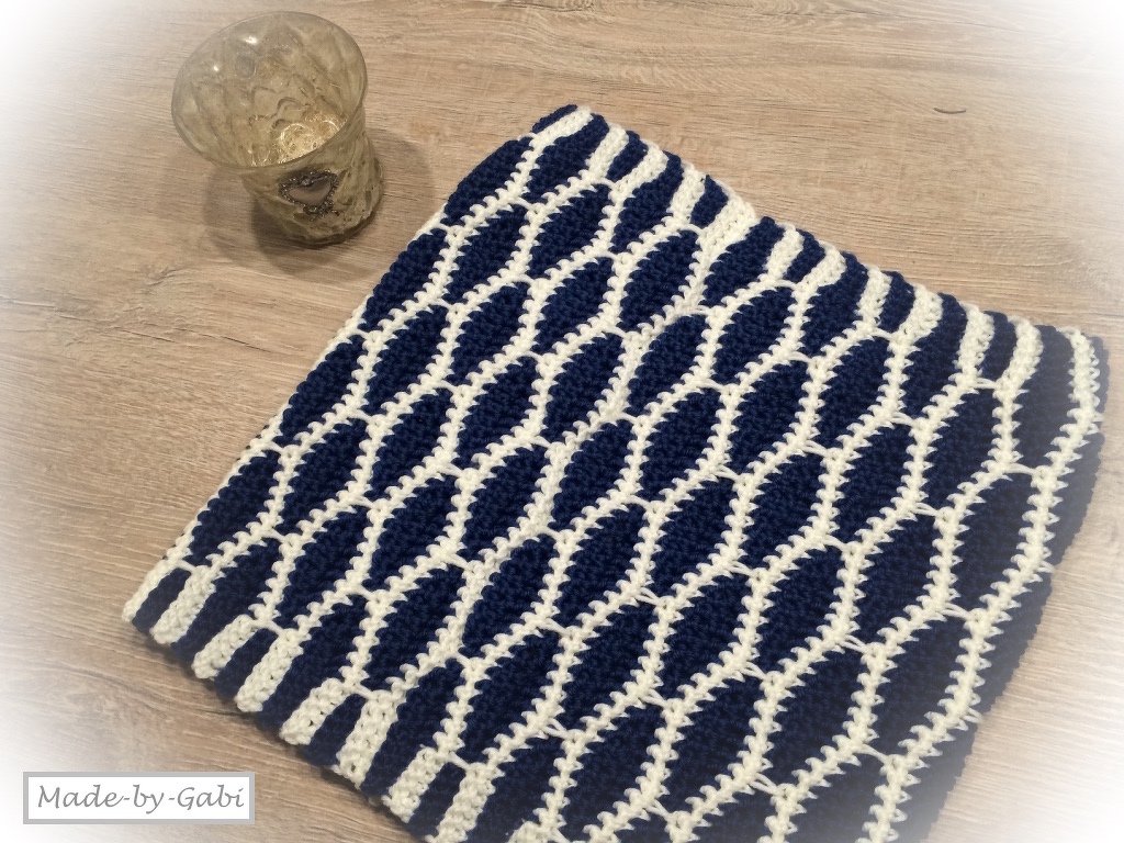 Gehäkelter Loopschal in Marineblau und Cremeweiß mit ovalem Reliefmuster auf Holztisch