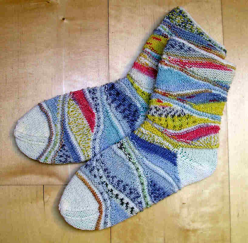Bunte handgestrickte Damensocken mit Streifen- und Strukturmustern auf Holzboden