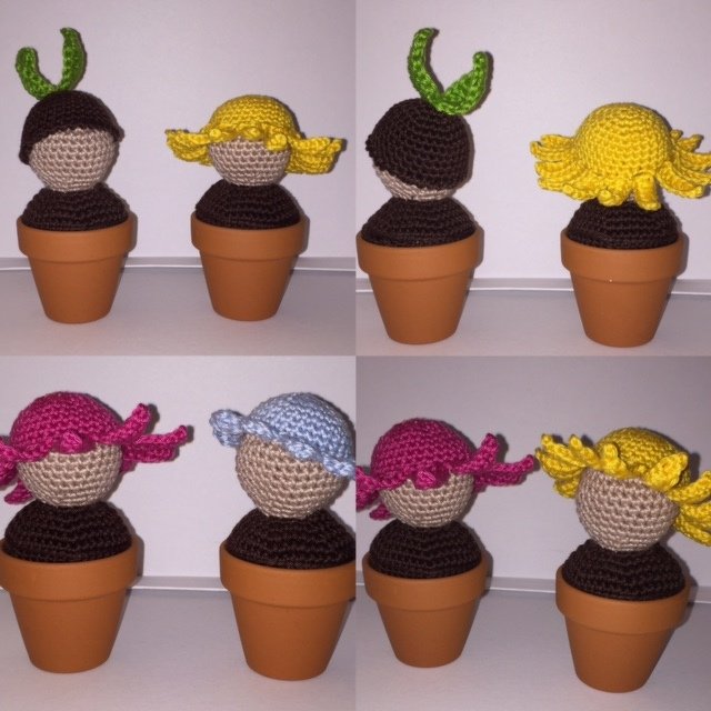 Acht gehäkelte Keimlinge in kleinen Terrakotta-Töpfen mit bunten Häubchen