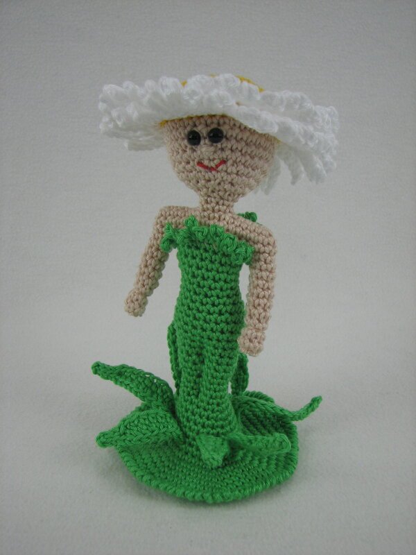 Gehäkelte Amigurumi-Puppe im Gänseblümchen-Design mit weißem Blütenhut und grünem Kleid.