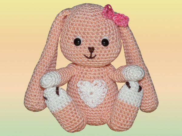 Rosa gehäkelter Osterhase (Amigurumi) mit Schlappohren, weißem Bauchherz, weißen Pfoten und pinker Schleife.