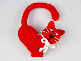 Rote gehäkelte Amigurumi-Katze mit herzförmigem Körper und weißer Schleife