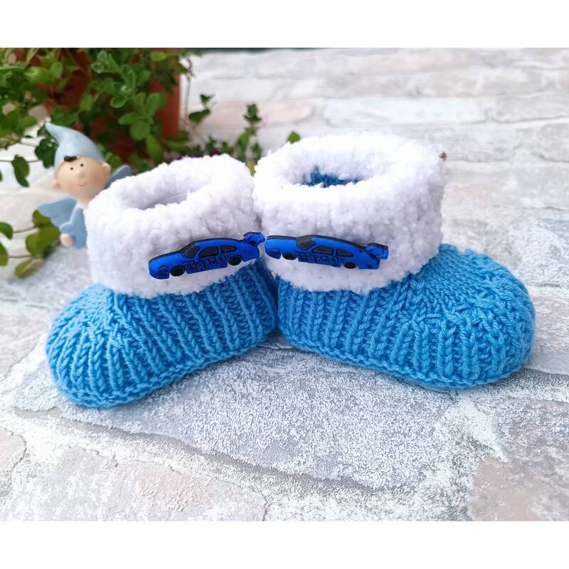 Blaue gestrickte Babyschuhe mit weißem flauschigem Rand und Auto-Applikationen