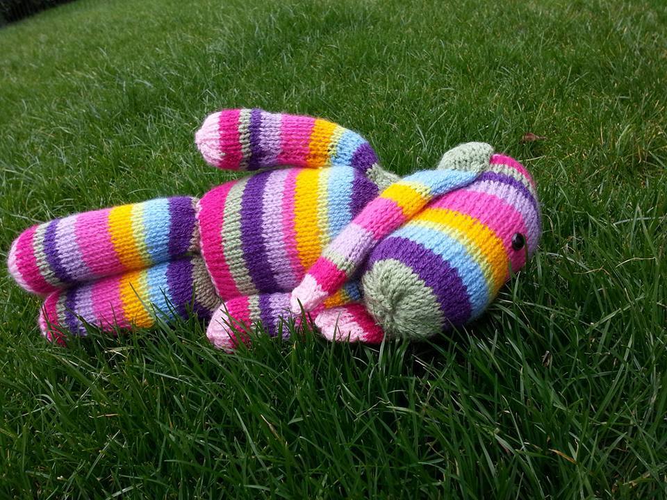 Farbig gestreiftes Amigurumi auf Gras, frühlingshafte Farbkombination