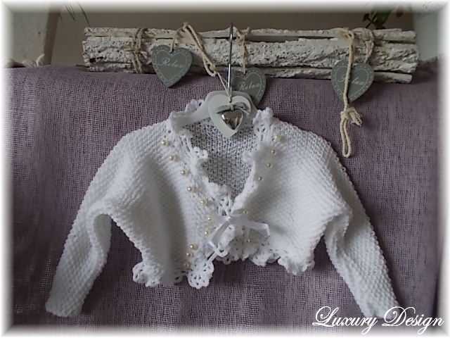 Weiße gestrickte Babyjacke mit Häkelspitze, Perlen und Bindeschleife an Aufhänger