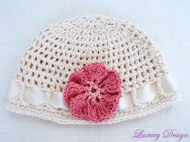 Hellbeige gehäkelte Mütze mit rosa Häkelblume und cremefarbenem Satinband