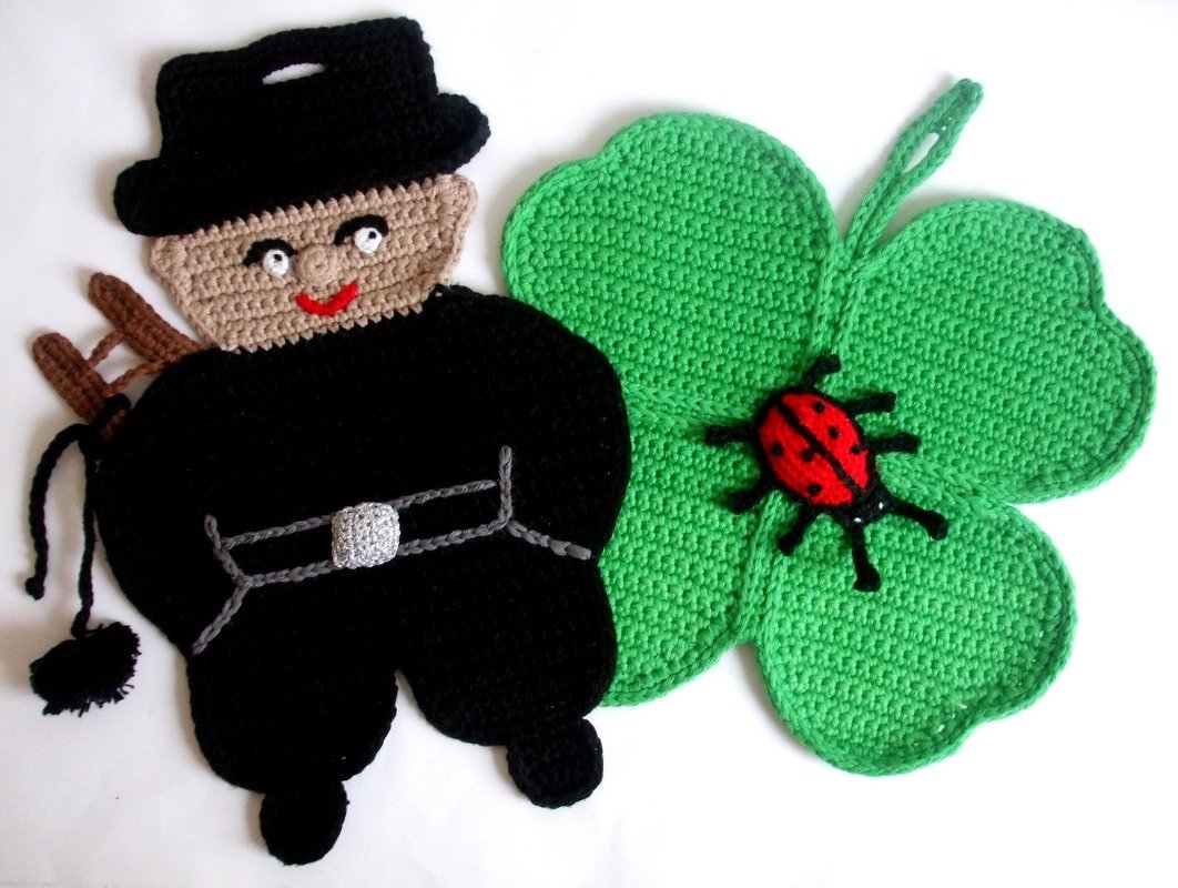 Gehäkelter Topflappen in Form eines vierblättrigen Kleeblatts mit Aufhängeschlaufe und ein gehäkelter Schornsteinfeger mit Leiter