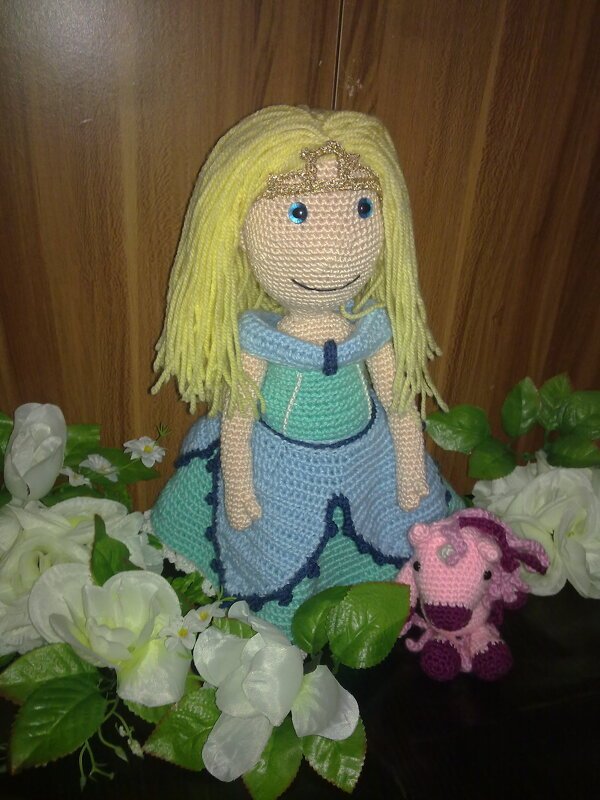 Gehäkelte Prinzessinnen-Puppe mit blondem Haar und blau-grünem Kleid neben einem rosa Einhorn.