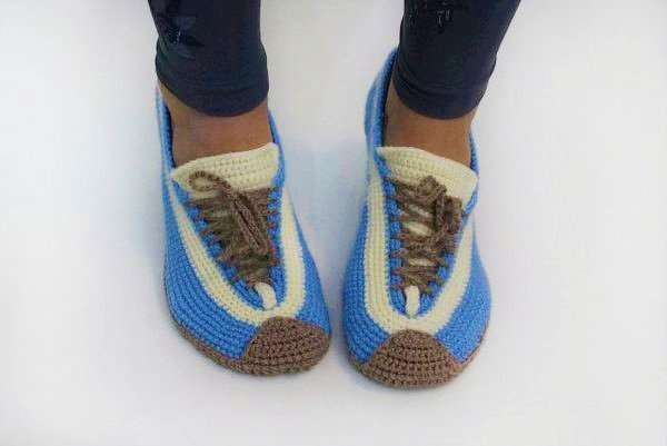 Paar gehäkelter Damen-Hausschuhe in Hellblau, Beige und Braun im Sneaker-Design an Füßen