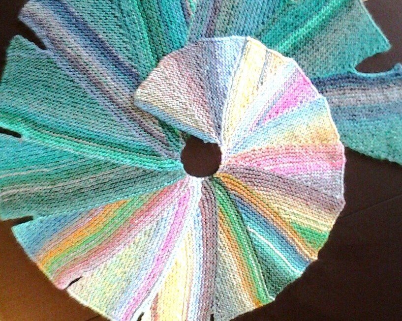 Kreisförmiges gestricktes Tuch aus keilförmigen, mehrfarbigen Segmenten in kraus-rechts-Struktur