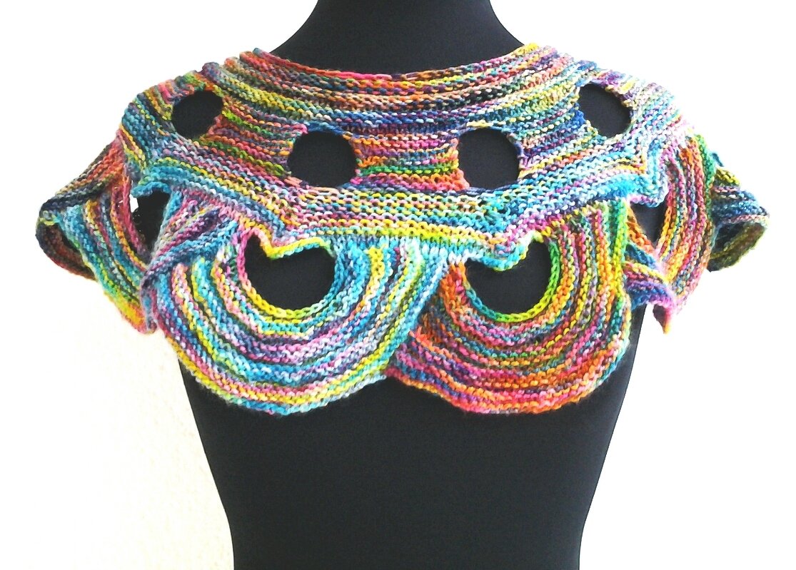 Bunter gestrickter Kragenschal mit runden und wellenförmigen Ausschnitten auf einer schwarzen Schneiderpuppe.